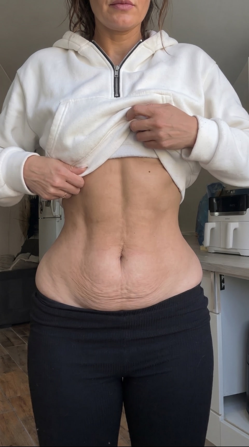Person lifting a sweatshirt to show their abdomen during a body check-in