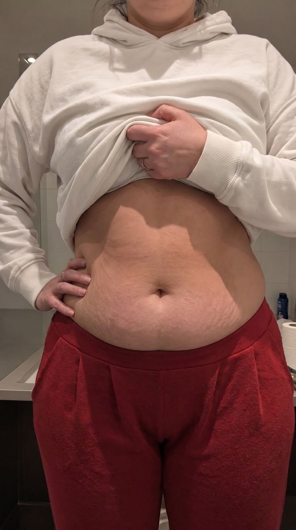 Person lifting a sweatshirt to show their abdomen during a body check-in